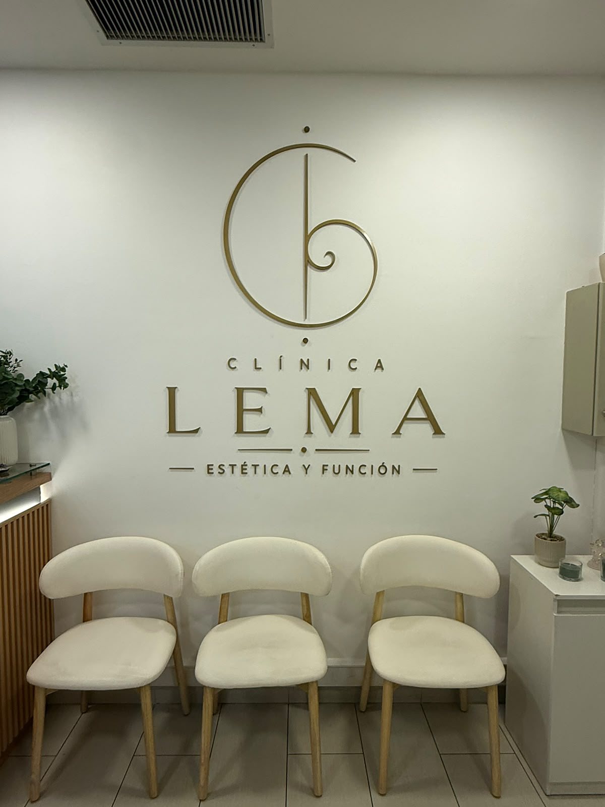 Logo de Clínica LEMA en la pared de la sala de espera, con sillas de espera