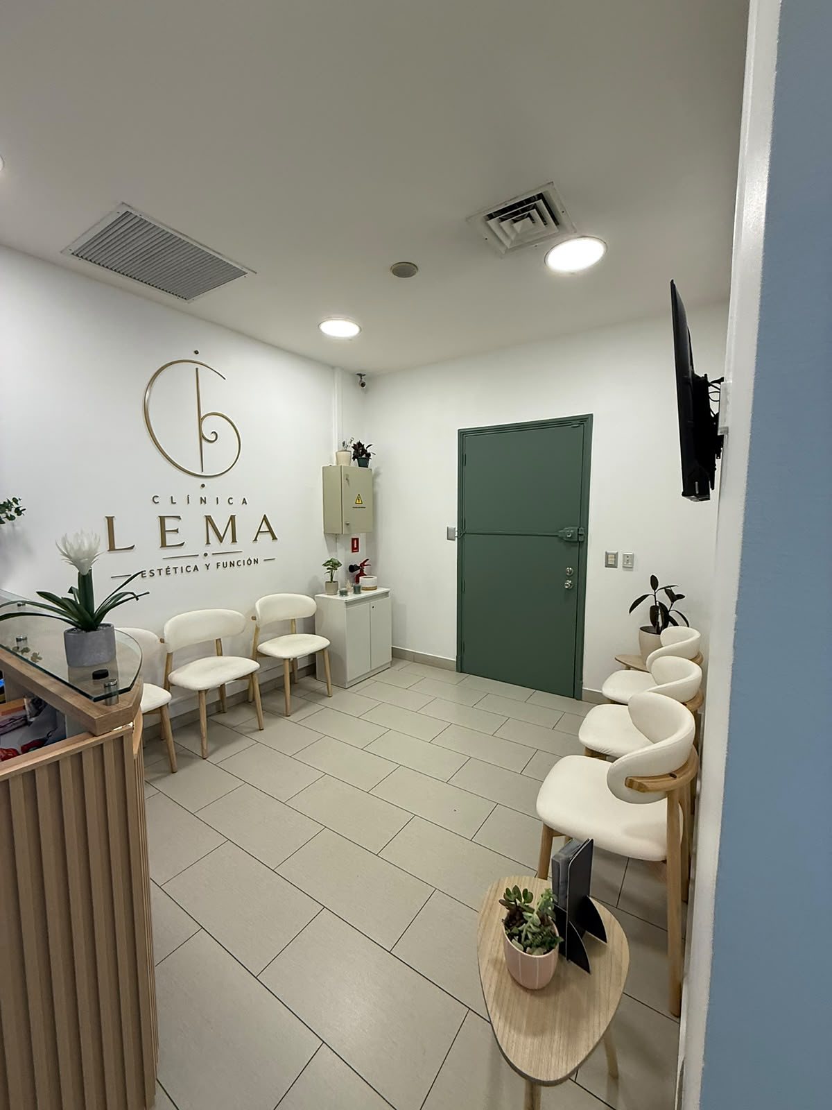 Sala de espera de Clínica LEMA con el logo en la pared y puerta verde