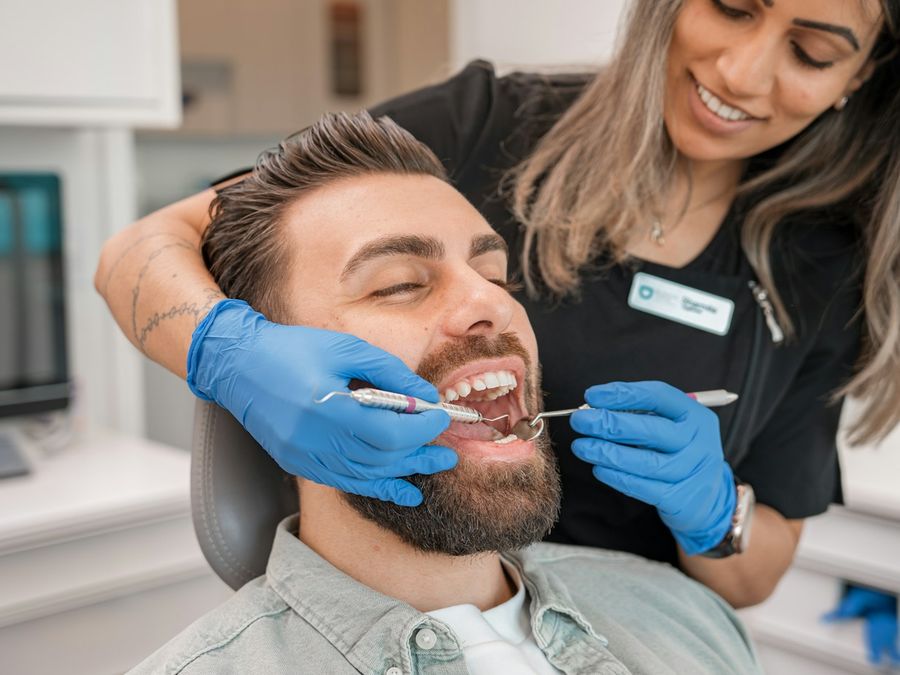 Dentista revisando los dientes de un paciente sonriente